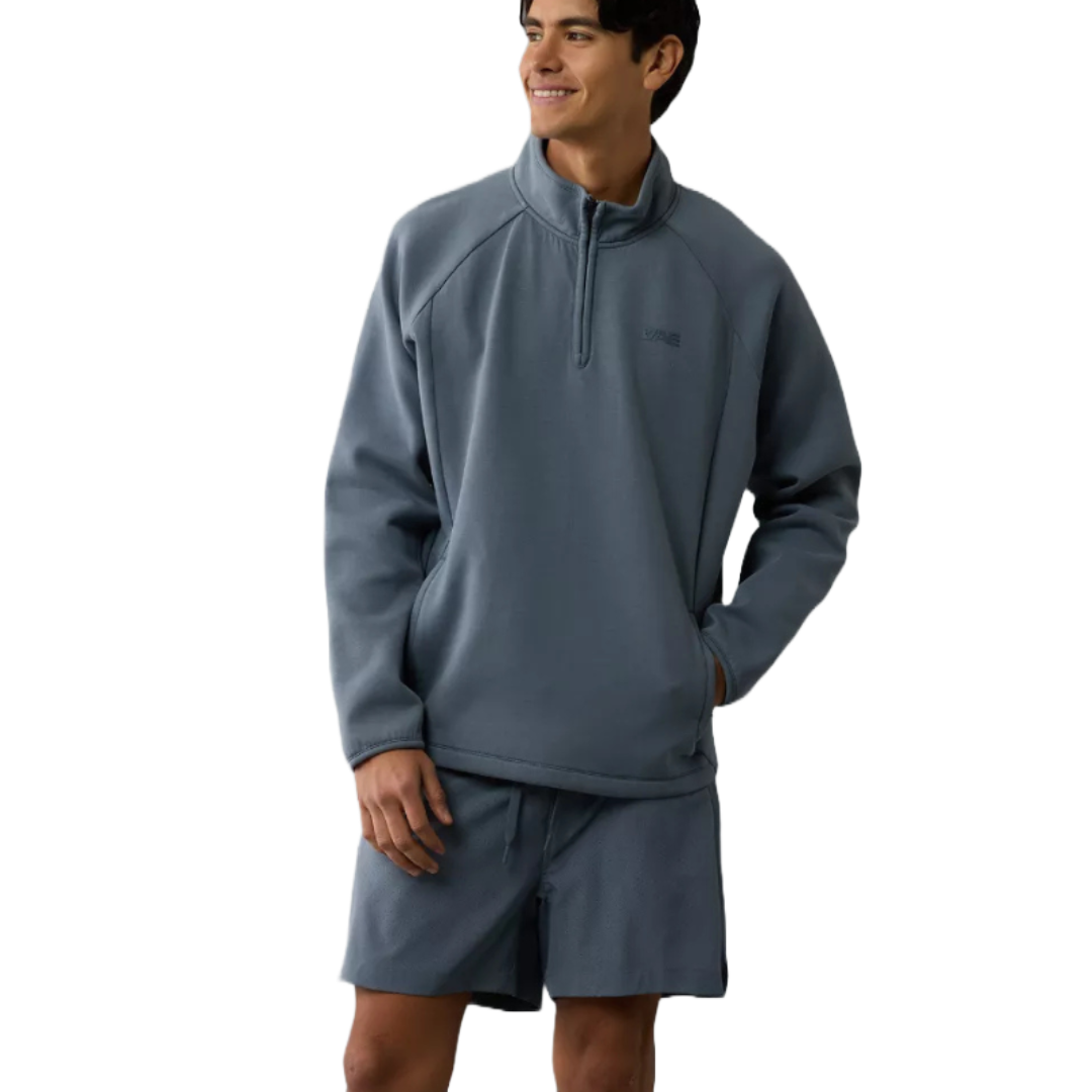 A blue Tech Fleece Quarter-Zip Sweatshirt featuring long sleeves, a high collar, and a quarter-length zipper, paired with matching shorts. The outfit has a casual, sporty appearance.