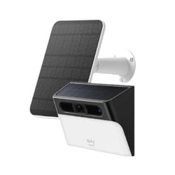 The image shows a solar-powered wall-mounted security camera with an attached solar panel. The camera is black and white, while the solar panel is positioned above to provide power.