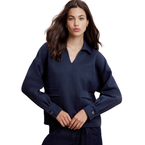 A woman is wearing a navy blue sweatshirt with a V-neck, collar, and buttoned cuffs. The sweatshirt features two patch pockets on the front, with a relaxed fit and long sleeves.
