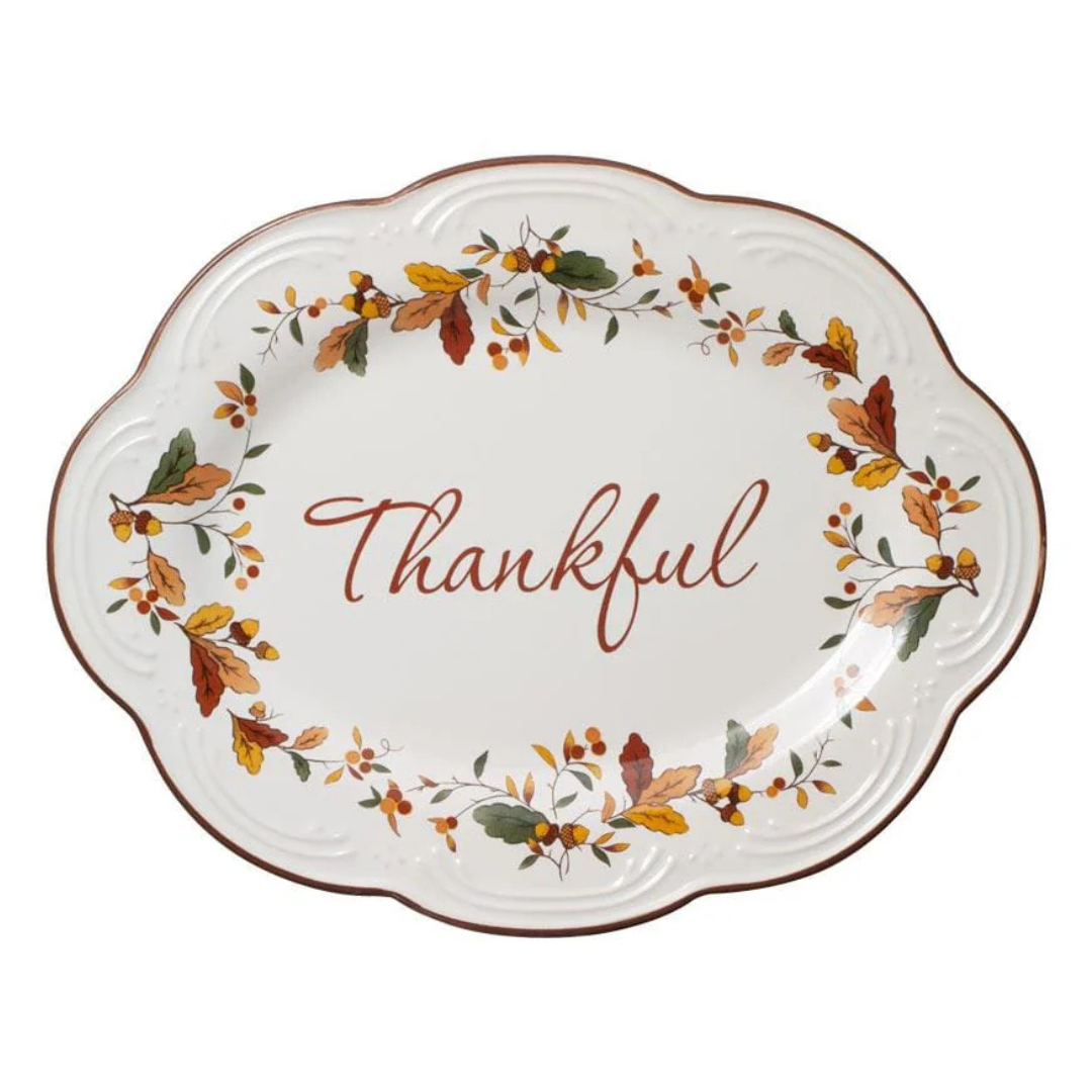 A decorative oval plate with the word \“Thankful\“ in the center, surrounded by an autumn-themed wreath of leaves and berries.