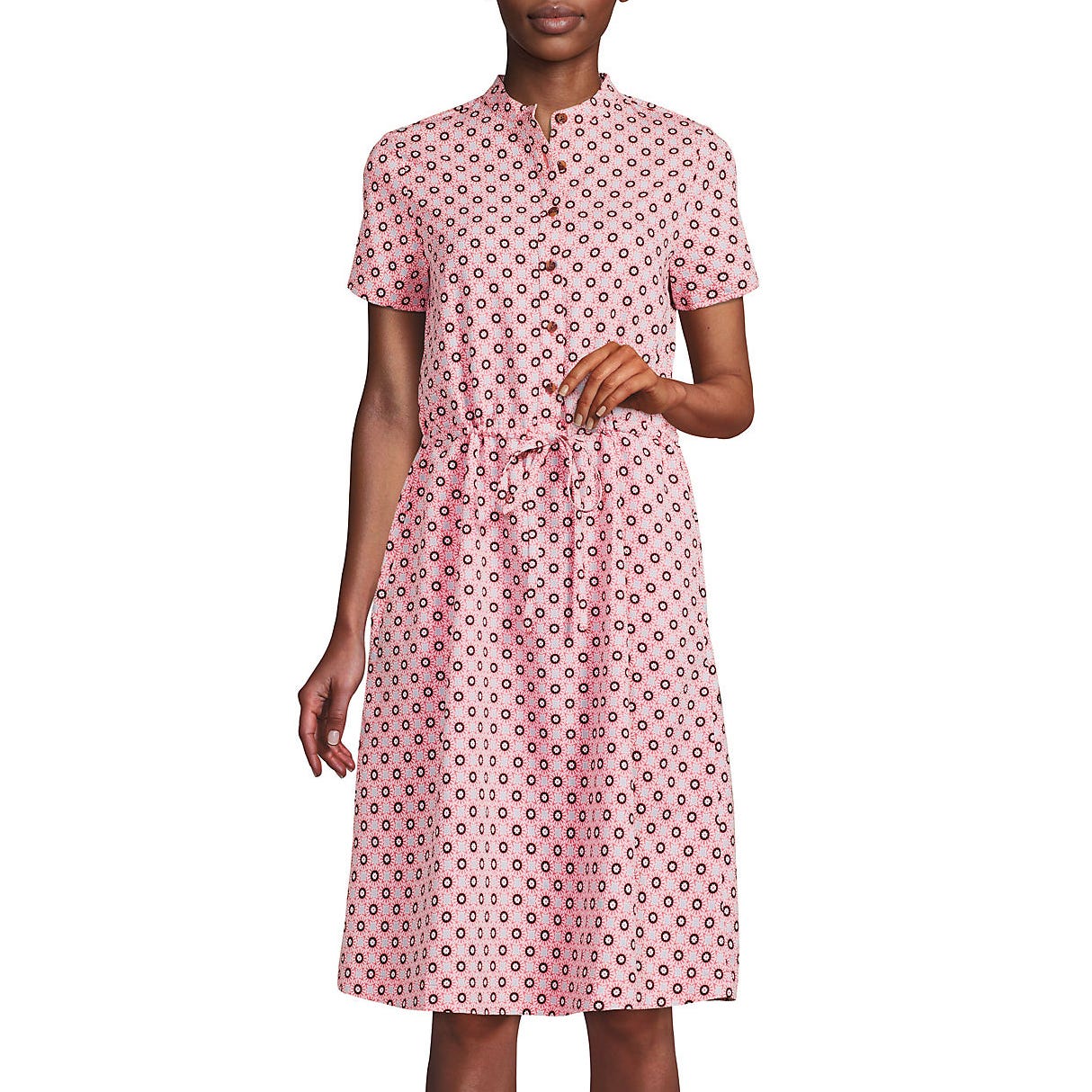 A person wearing a short-sleeved, knee-length pink dress with a geometric circular pattern and a drawstring waist.
