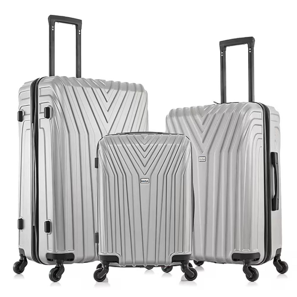 Three silver hard-shell suitcases with handles and four wheels each, featuring a V-shaped pattern design.