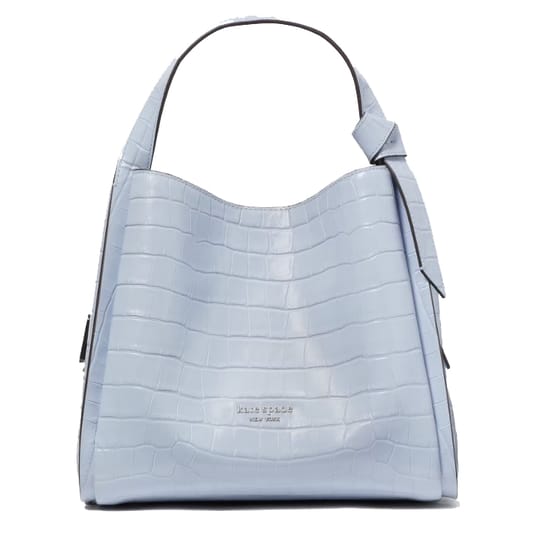Light blue tote bag with a crocodile-embossed texture and the \“kate spade new york\“ logo. Features a single top handle with an adjustable strap detail.