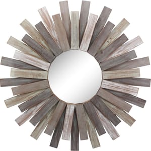 A round mirror features a wooden sunburst frame with staggered, weathered planks radiating outward in varied lengths and shades of gray and brown.
