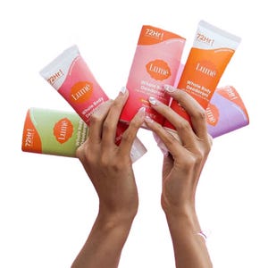 Hands holding five tubes of Lume Whole Body Deodorant in various colors, labeled with \“72HR\“ for 72-hour protection.