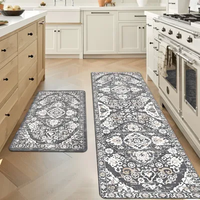 Two intricately patterned kitchen mats are placed on the floor in front of cabinets and a stove, offering both style and comfort in a kitchen setting.
