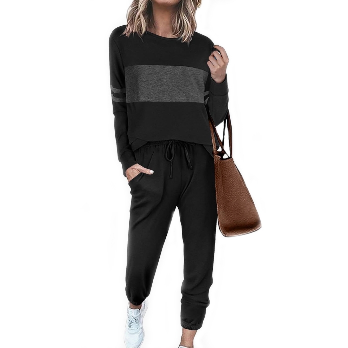 A person is wearing a matching black loungewear set with a dark gray stripe across the top, black jogger pants, and light blue sneakers, carrying a brown textured tote bag.
