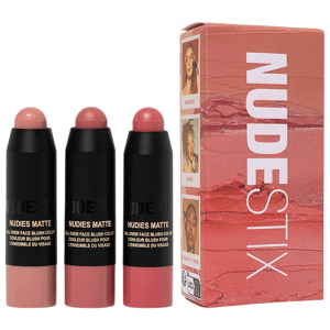 Three Nudestix Nudies Matte blush sticks in shades Bare Back, Cherie, and Naughty N' Spice are displayed alongside their packaging, featuring images of models using the blushes.