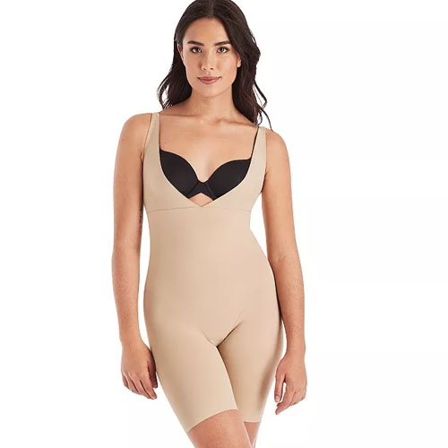 A woman wears a beige, sleeveless, full-body shapewear garment with shorts, designed to provide a slimming effect, paired with a black bra.