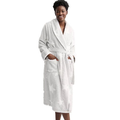 A woman wears a white bathrobe with a subtle polka dot pattern, featuring a shawl collar, waist tie, and two front pockets.