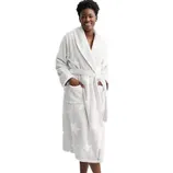 A woman wears a white bathrobe with a subtle polka dot pattern, featuring a shawl collar, waist tie, and two front pockets.