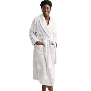 A woman wears a white bathrobe with a subtle polka dot pattern, featuring a shawl collar, waist tie, and two front pockets.