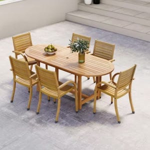 A wooden outdoor dining set with an oval table and six chairs on a stone patio, featuring a potted plant and a bowl of fruit on the table.