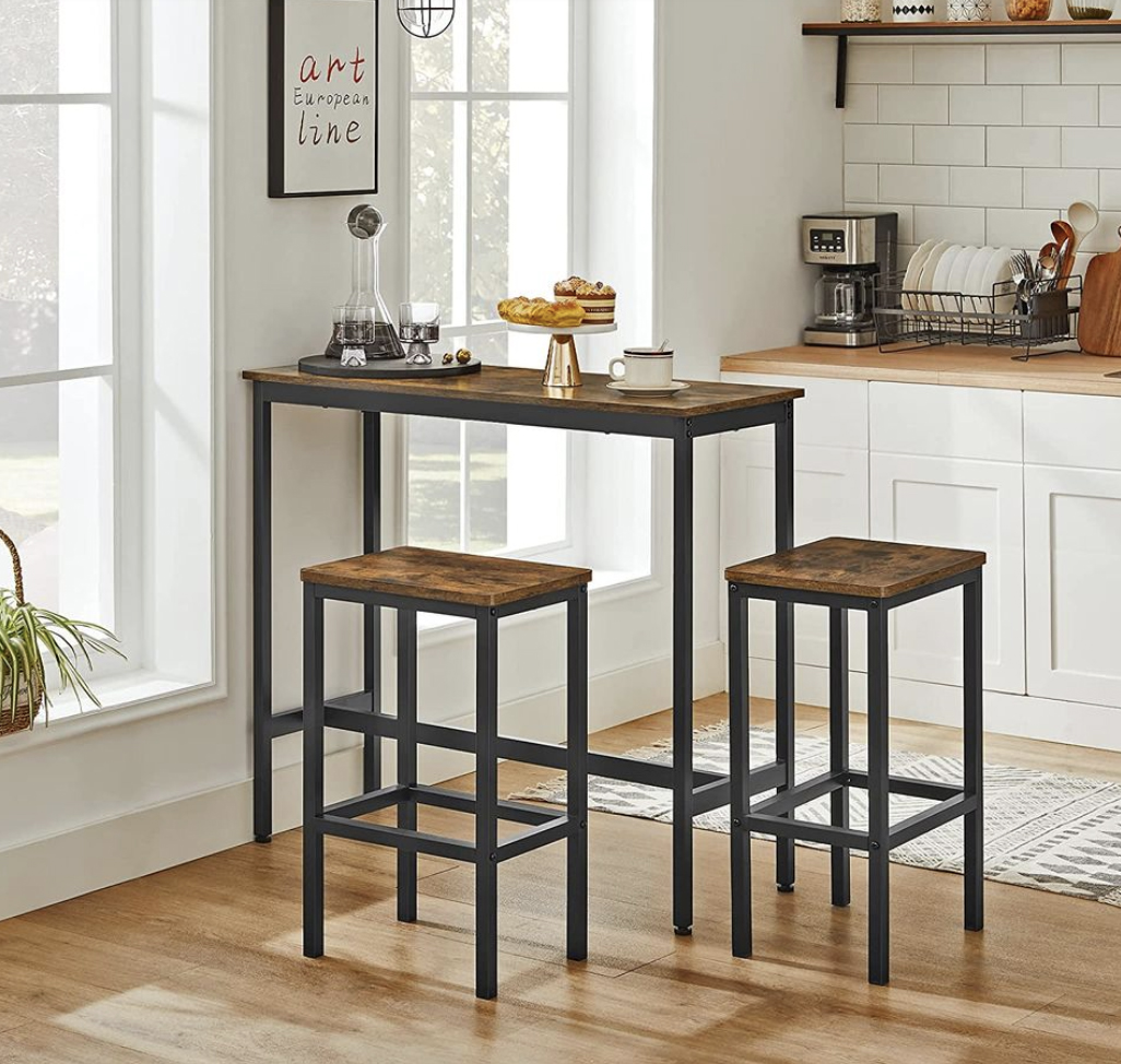 A bar table with two matching stools, featuring a dark metal frame and wooden tops.