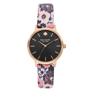A Kate Spade Floral Metro Watch with a black dial, gold-tone case, and a floral-patterned strap in shades of pink, black, and white.