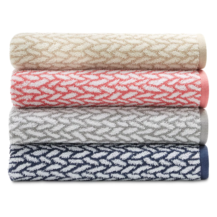 Four rolled towels with a chevron pattern in cream, coral, gray, and navy colors are stacked in a neat pile.