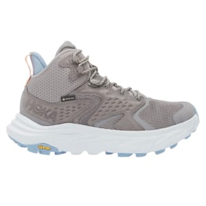 Hoka Anacapa hiking boots are designed with a high-top style, Gore-Tex material for waterproofing, and Vibram soles for durability. They feature a light gray color with a padded collar and loop tab for easy wear.