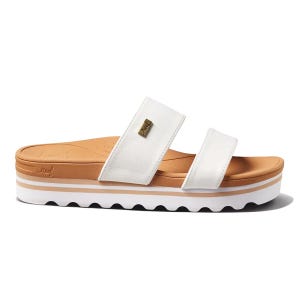 Reef Horizon Slide Sandals feature a dual-strap design in white faux leather, a tan footbed, and a white platform sole with a wavy tread pattern. They have a small metal brand logo on the strap and provide a stylish, casual look.