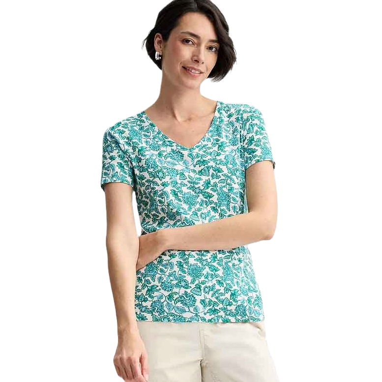 A woman is wearing a Croft & Barrow Essential V-Neck Tee, featuring a green and white floral pattern, short sleeves, and paired with light-colored pants.