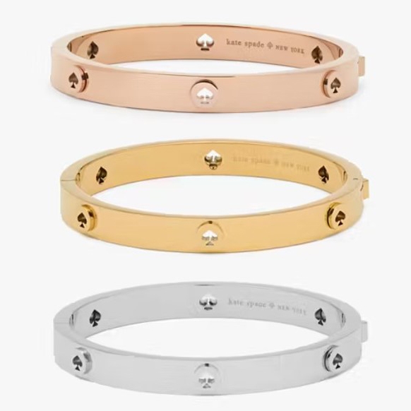 Three bangle bracelets in rose gold, gold, and silver colors displayed with a designer logo engraved.