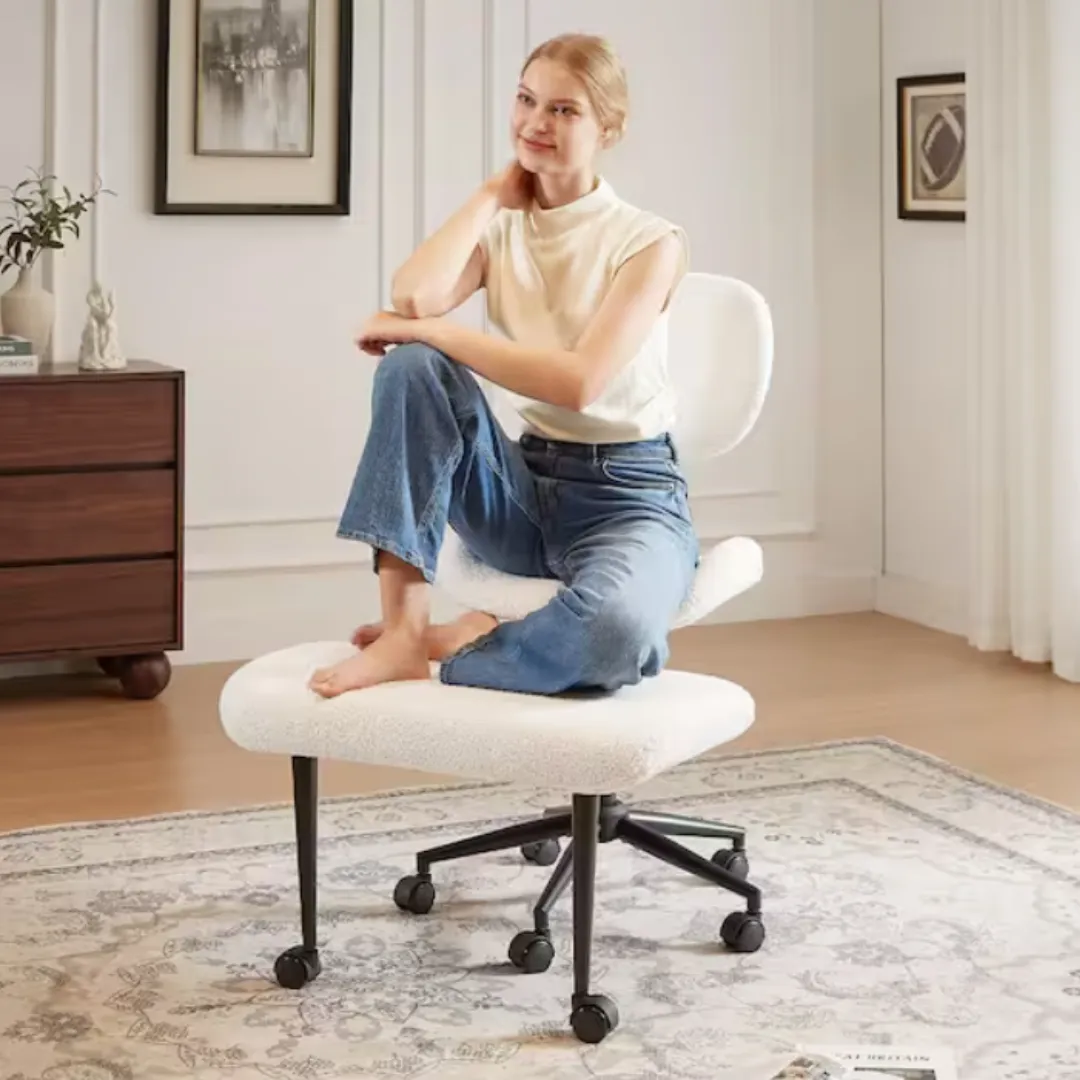 A woman sits cross-legged on an adjustable office chair with a cushioned seat and backrest, set on a decorative rug in a cozy, modern room with minimalistic decor.