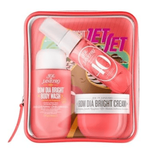Sol de Janeiro Bom Dia Bright set includes a body wash, cream, and body mist in pink packaging, all contained in a transparent zippered case.