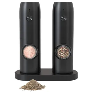 A set of two black electric grinders, one containing pink Himalayan salt and the other mixed peppercorns, placed on a charging dock. A small pile of ground pepper is in front of the set.