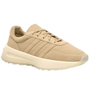 A beige sneaker with a minimalist design, featuring a cushioned sole and subtle stitching details.