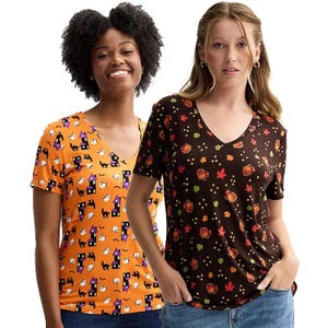 Two women wearing V-neck graphic t-shirts, one with a Halloween theme and the other with an autumn leaves pattern.