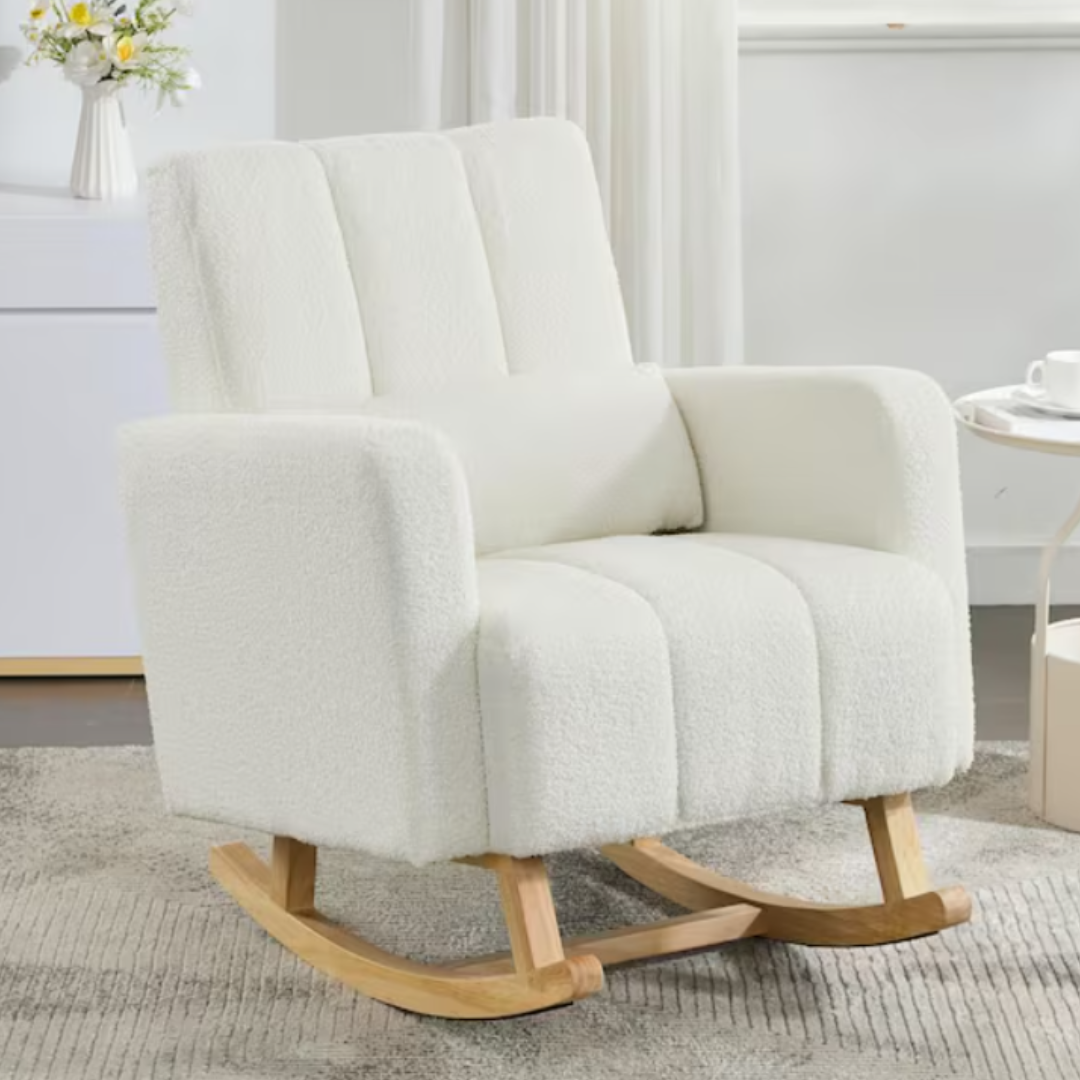 White modern rocking chair with soft upholstery and light wooden rockers, placed on a textured rug beside a small round table and a floral vase.