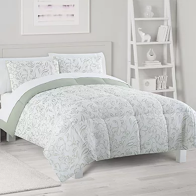 A comforter set with a white and light green floral pattern, including two matching pillow shams, displayed on a bed in a room with white furniture.