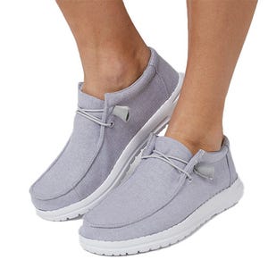 Gray casual slip-on shoes with white soles and decorative laces, designed for comfort and easy wear.