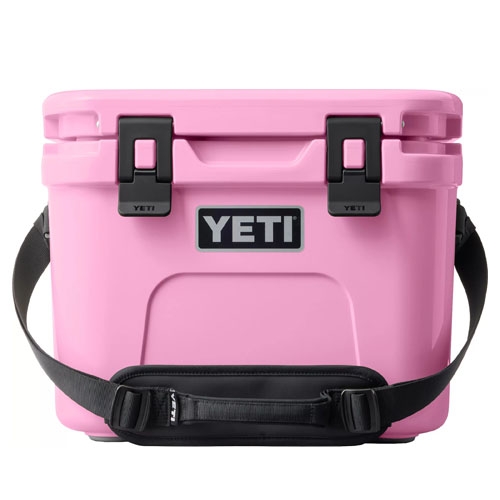 Pink YETI cooler with black latches, brand logo on the front, and a black shoulder strap.