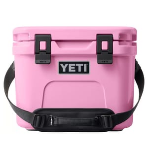 Pink YETI cooler with black latches, brand logo on the front, and a black shoulder strap.