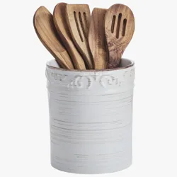 A decorative white ceramic holder containing a set of wooden kitchen utensils, including slotted spoons and spatulas.