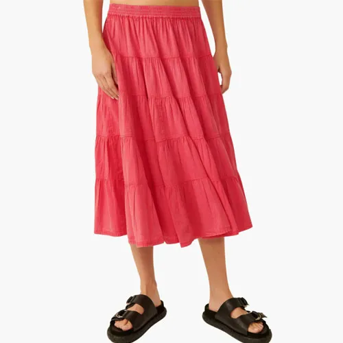 A person wearing a pink tiered midi skirt paired with black sandals.