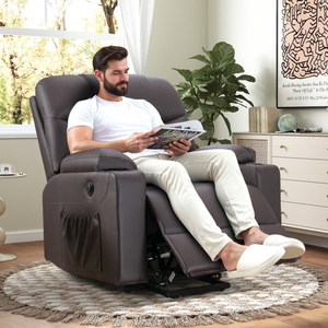 A man sits in a reclining chair with an attached side pocket, reading a magazine. The room features light décor, a round rug, a small side table with a plant, and a dresser with a Keith Haring artwork on the wall.