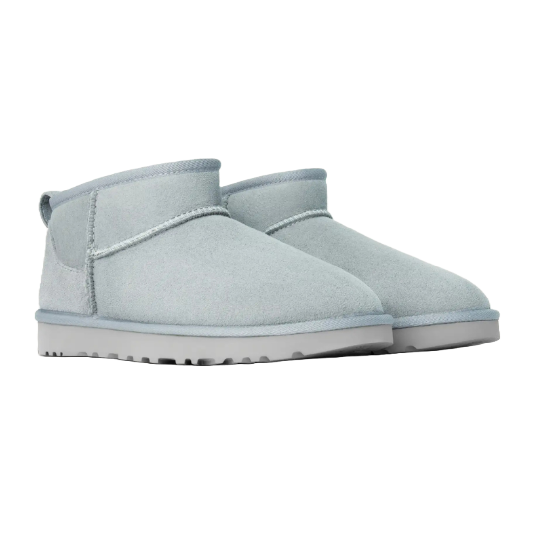 Light gray ankle-high suede boots with a low cut and a flat sole, featuring a loop pull tab at the back.