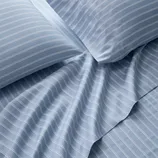 Blue bedsheets with white pinstripes, including pillowcases and a flat sheet, arranged to show texture and design.