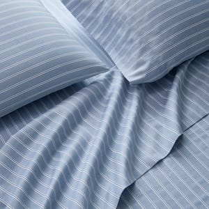 Blue bedsheets with white pinstripes, including pillowcases and a flat sheet, arranged to show texture and design.