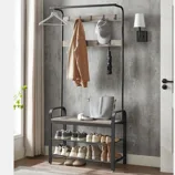 A modern entryway hall tree features a black metal frame with hooks for hanging coats and hats, a shelf for bags, and two lower shelves for storing shoes.