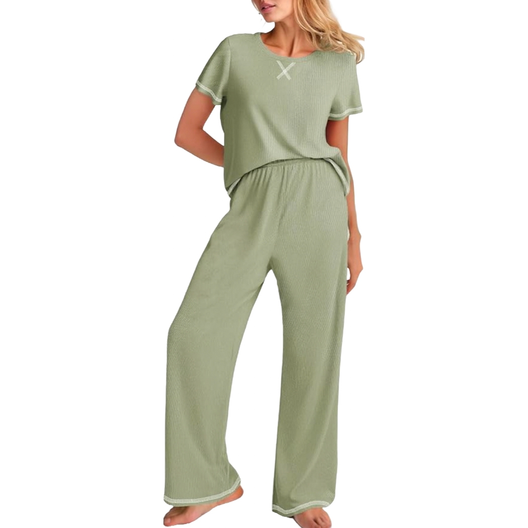 A woman is wearing a light green loungewear set with a short-sleeve top featuring a small \“X\“ design on the chest and matching wide-leg pants.
