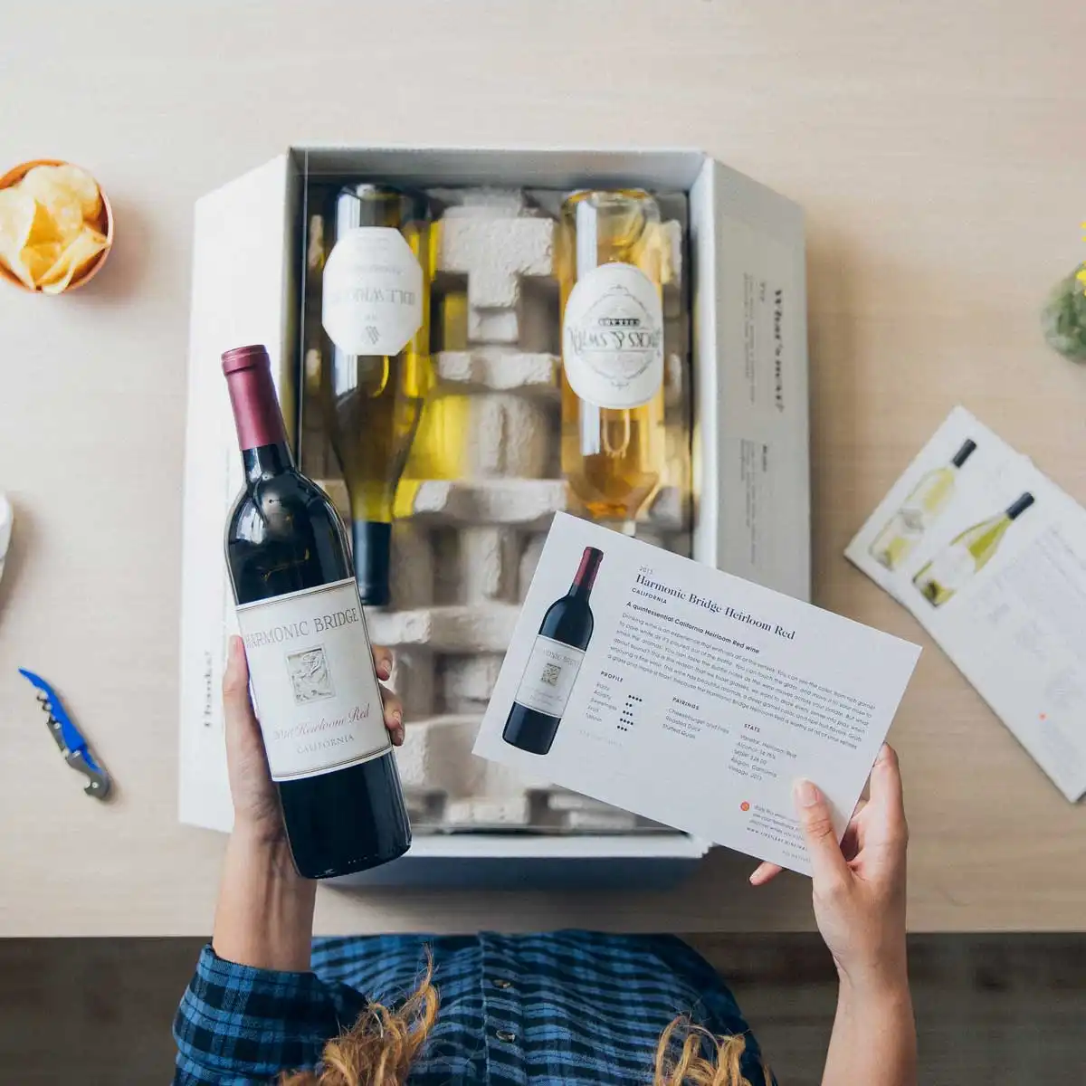 A wine subscription box featuring six award-winning wines, including a mix of red and white bottles such as \“Harmonic Bridge.\“ The set includes detailed cards describing each wine's characteristics and origin.