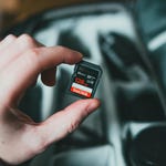 A hand is holding a 128 GB SanDisk Extreme Pro SD card.