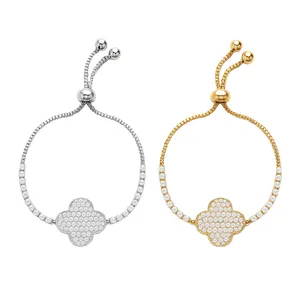 Two adjustable bracelets, one in silver and the other in gold, feature a central clover-shaped charm encrusted with clear crystals, connected by a beaded chain.