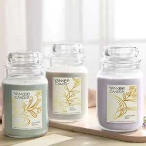 Three Yankee Candle jars are shown: Serenity Stone (sea moss, dune grass, blue chamomile), Slow Bloom (jasmine, sandalwood, whispering willow), and Lavender Bliss (lavender, cedarwood, orchid petals).