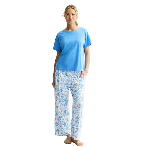 A woman is wearing a blue short-sleeve top and white pajama pants with blue tropical patterns.