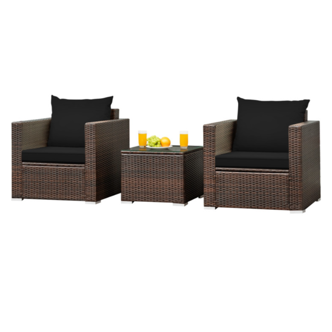 Brown wicker patio conversation set with two armchairs featuring black cushions and a square side table with a glass top, decorated with two glasses of juice and a small fruit arrangement.