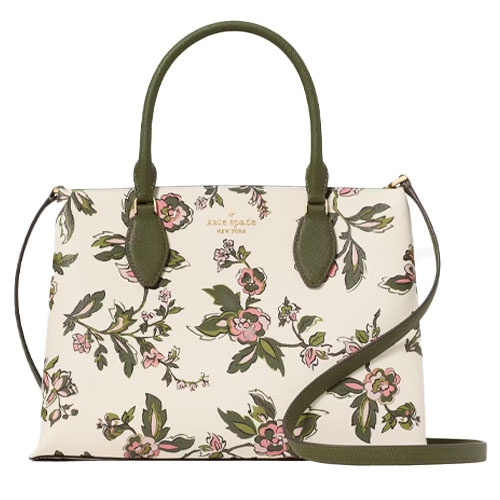 A floral-patterned handbag with green handles and a matching strap, showcasing a white background with pink and green floral designs. Brand name is visible at the top center.