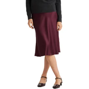 A knee-length, A-line skirt made from deep burgundy silk, featuring a smooth, lustrous texture. It's paired with a dark sweater and low-heeled, glossy ankle-strap shoes.